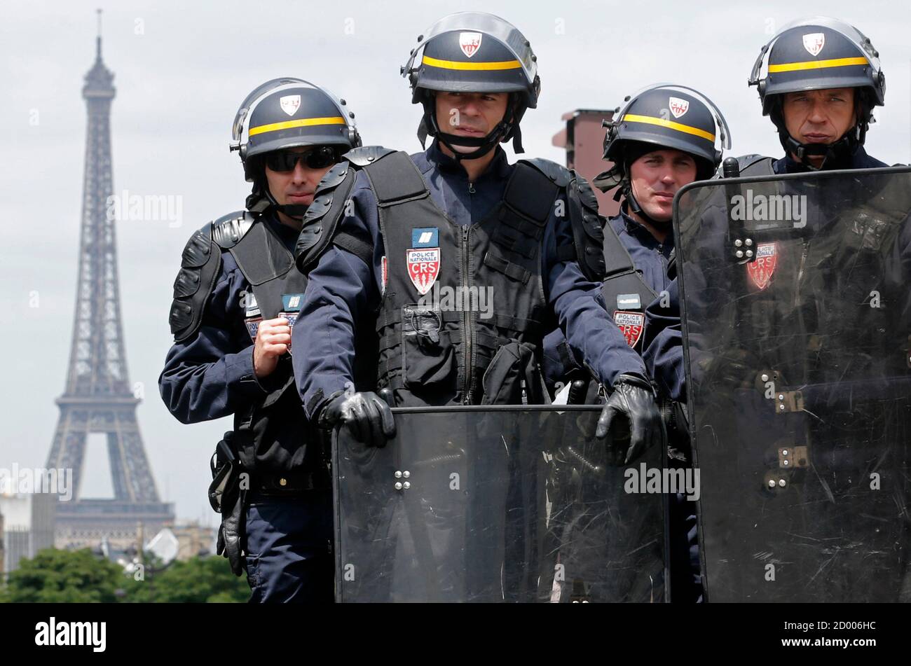 French CRS riot police officers are seen with the Eiffel Tower in the background as they secure the area next to the Gare Montparnasse station after railway workers staged a protest on the tracks against a planned reform of the sector in Paris, June 17, 2014. Workers at the SNCF train operator continue their strike which is in it's seventh day over a rail reform bill due to go to parliament today. The strike, which continues on Tuesday, is one of the longest France has seen in years and has disrupted services since it began on June 10. REUTERS/Christian Hartmann (FRANCE - Tags: BUSINESS CIVIL  Stock Photo