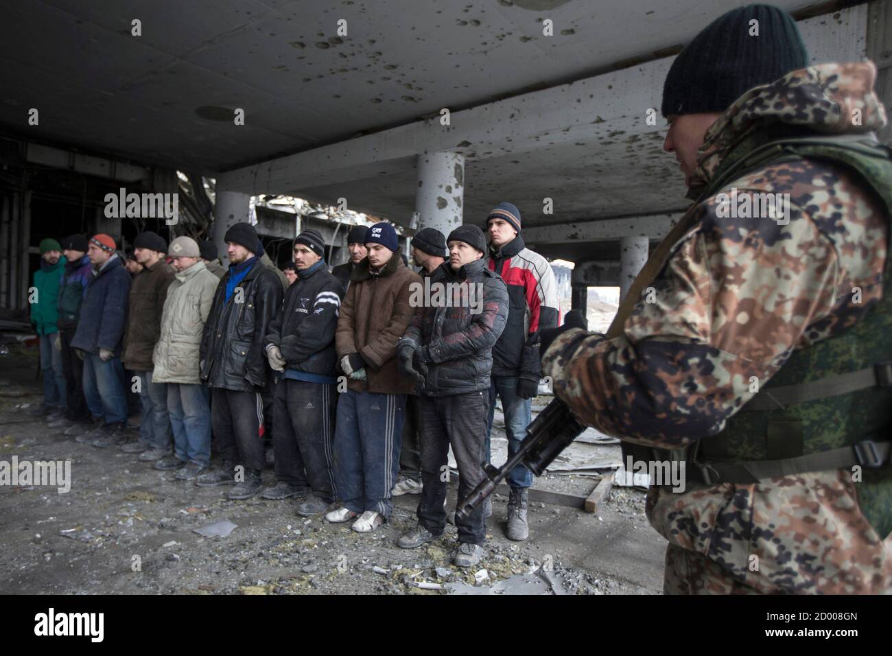 An armed man of the separatist self-proclaimed Donetsk People's Republic army (R) guards Ukrainian war prisoners in the damaged Donetsk airport , February 26, 2015.  REUTERS/Baz Ratner (UKRAINE - Tags: POLITICS CIVIL UNREST CONFLICT MILITARY) Stock Photo
