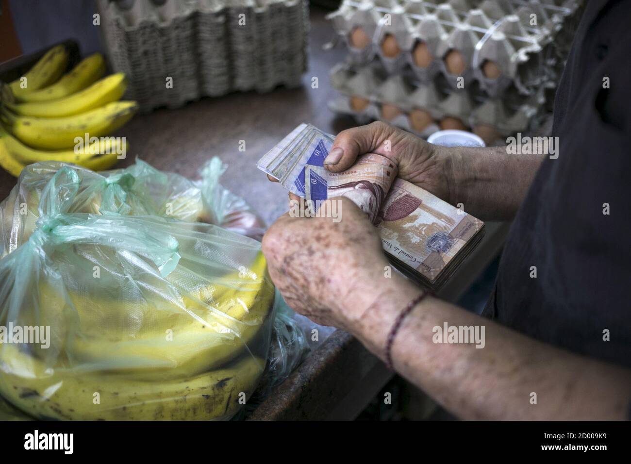 A clerk counts Venezuelan bolivar banknotes after selling goods to a customer at a fruit and vegetable store in Caracas July 10, 2015. A debilitating recession and a drop in oil prices have harmed the OPEC nation's ability to provide dollars through its complex three-tiered currency control system, pushing up the black market rate at a dizzying speed. The bolivar sank past 600 per U.S. dollar on Thursday, compared with 73 a year ago, according to anti-government website DolarToday. REUTERS/Marco Bello Stock Photo