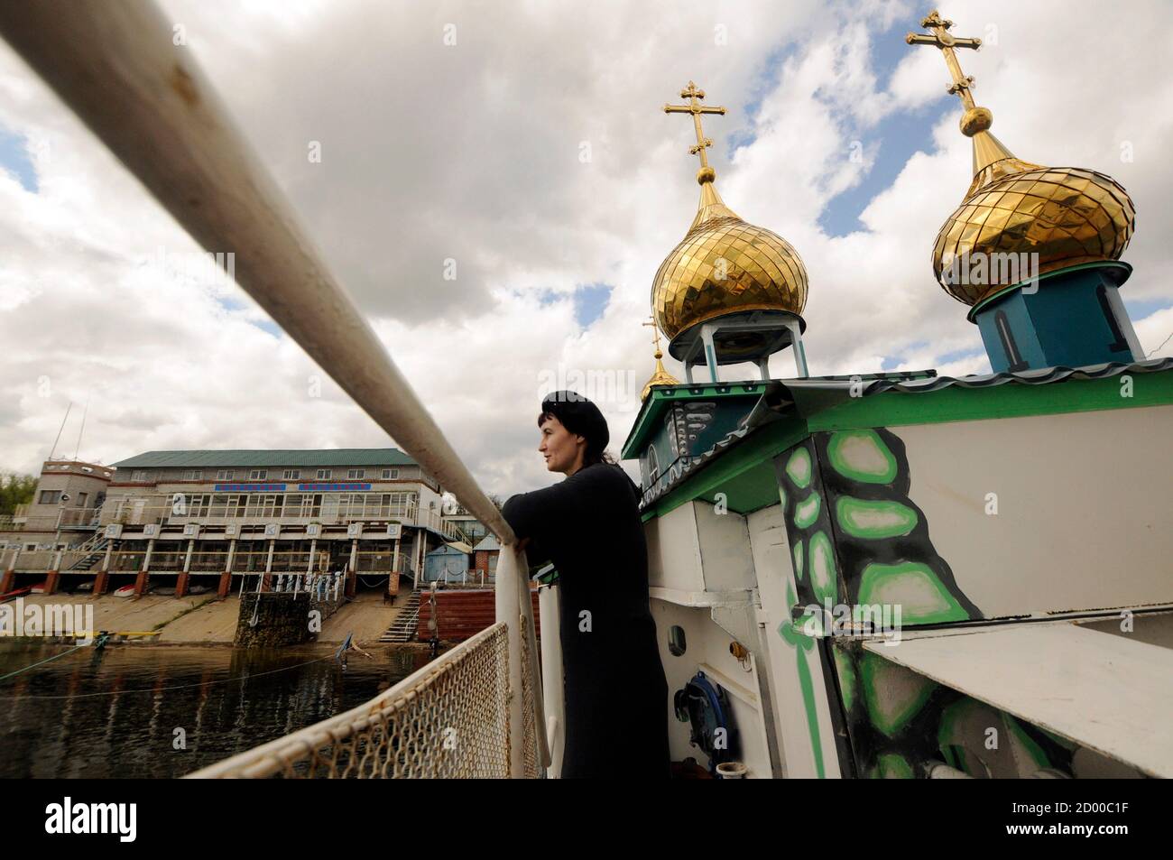 A woman stands onboard the Saint Vladimir floating Orthdox Christian temple tied up at a mooring on the Volga river in the southern city of Volgograd May 10, 2011. The self-propelled ship-temple which bears the full name 'Grand Prince St. Vladimir, Equal-to-the-Apostles' was reconstructed on the base of a landing ship and christened October 31, 2004, according to its builders.  REUTERS/Sergei Karpov  (RUSSIA - Tags: RELIGION SOCIETY ODDLY TRANSPORT) Stock Photo