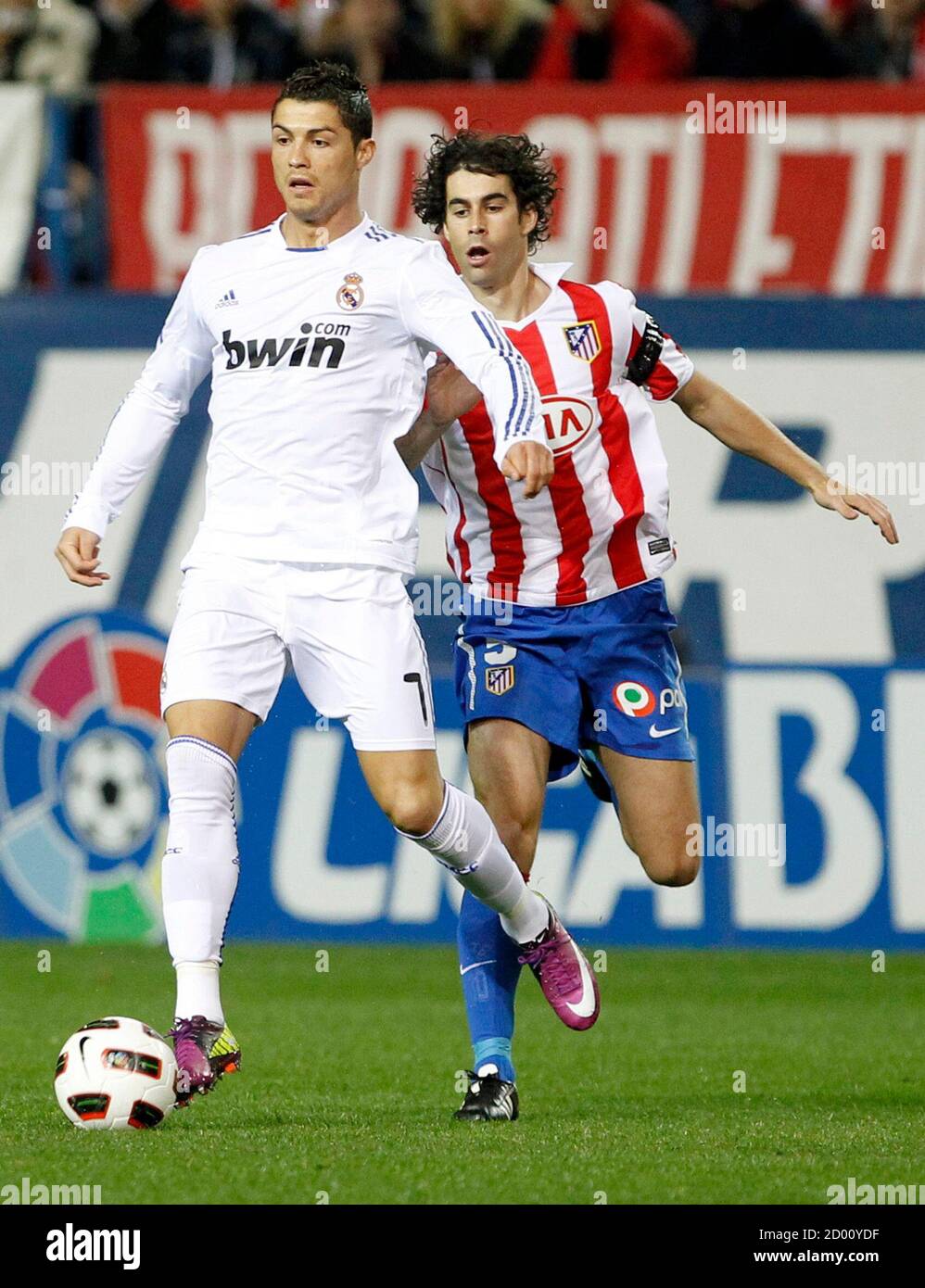 Real Madrid's Cristiano Ronaldo (L) runs with the ball past Atletico  Madrid's Tiago during their Spanish first division soccer match at Vicente  Calderon stadium in Madrid March 19, 2011. REUTERS/Paul Hanna (SPAIN -