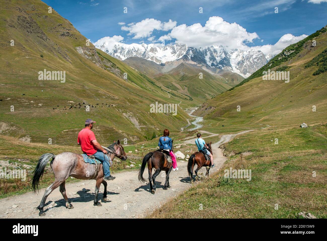 Horse riding in the foothills of Mount Shkhara (the highest mountain in Georgia), Svaneti region, Caucasus mountains, Georgia. Stock Photo