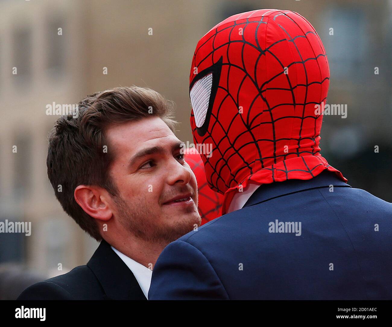 Actor Andrew Garfield messes around with a friend wearing a Spider Man mask  at the world
