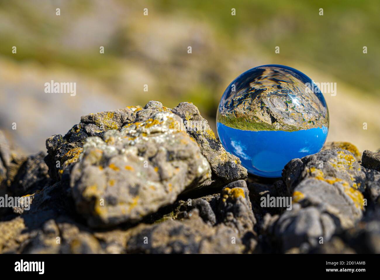 Photography Crystal Photo Ball showing upside down reflection of sky beach and waves balanced on rocks on sandy beach. Stock Photo