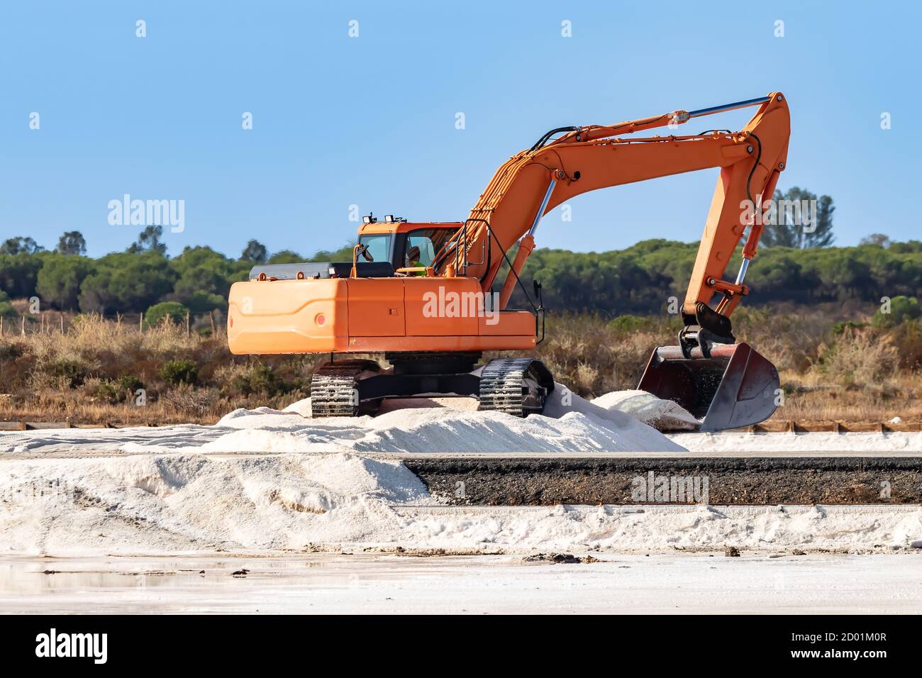 Excavator stacking sea salt. The traditional production of sea salt is