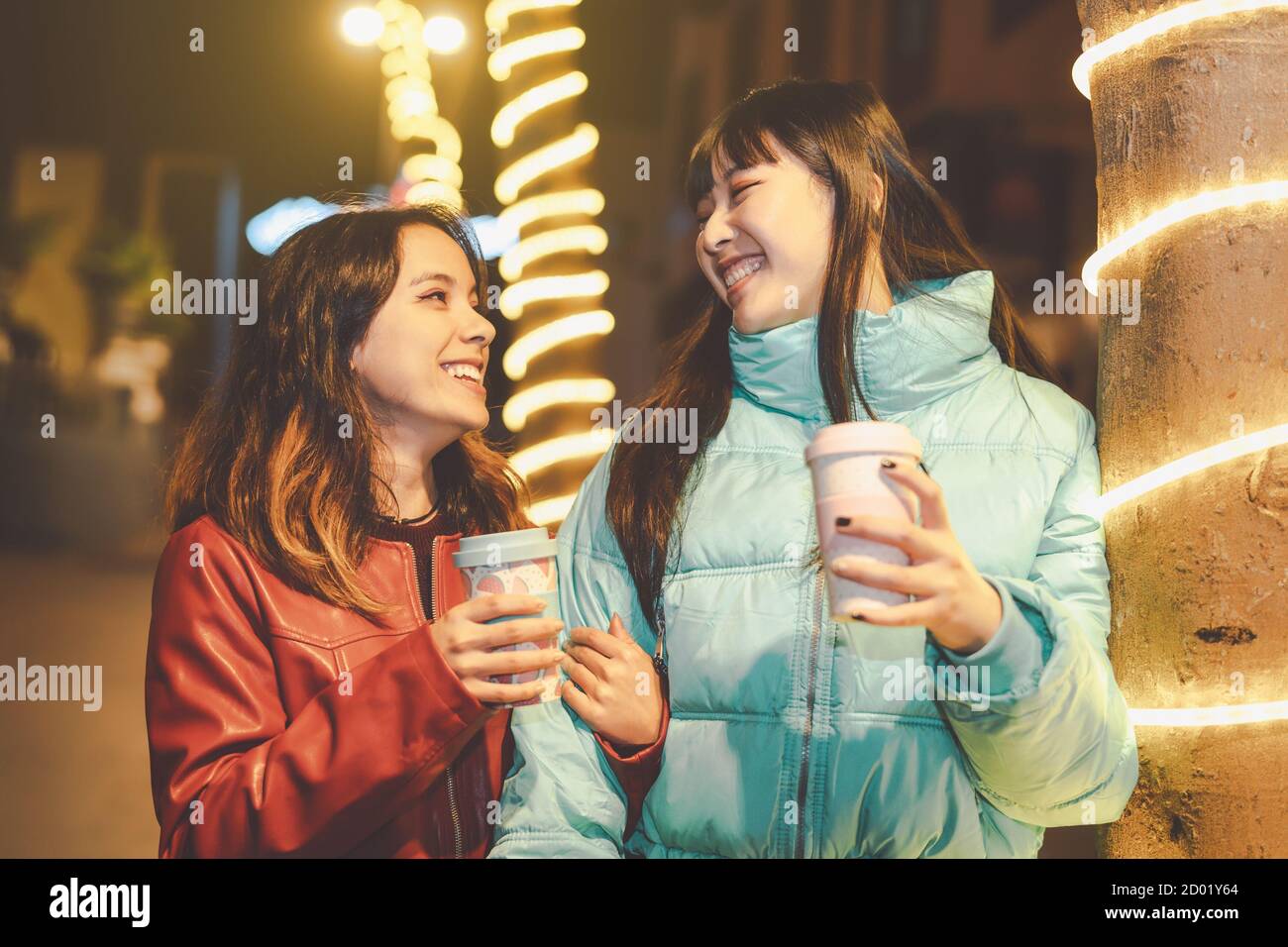 Happy friends walking in city while drinking coffee - Young girls having fun sharing time together outdoor Stock Photo