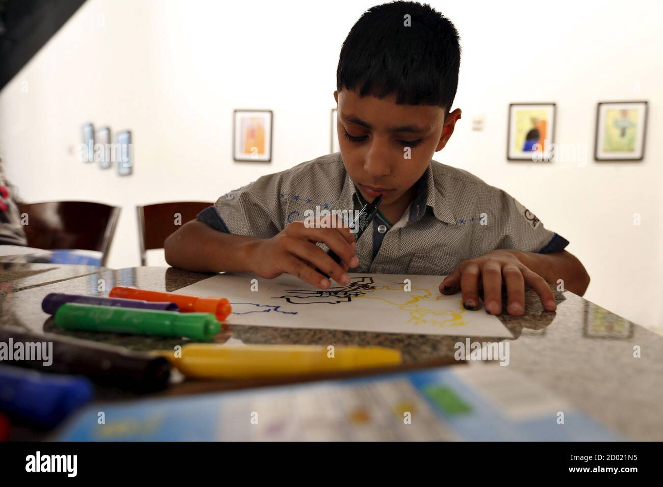 Tariq Khamees, who is blind, smells as he colors at an art exhibition in Amman, Jordan, June 17, 2015. The royal academy for blind students provides recreational and creative opportunities for a number of blind and visually impaired children, by teaching them drawing, and how to distinguish between colours through the use of smell, where each colour is characterized in a distinctive odour. The academy is holding its first student art exhibition and proceeds go back to the children to encourage them to continue drawing, according to their artist teacher. Picture taken June 17, 2015. REUTERS/Muh Stock Photo