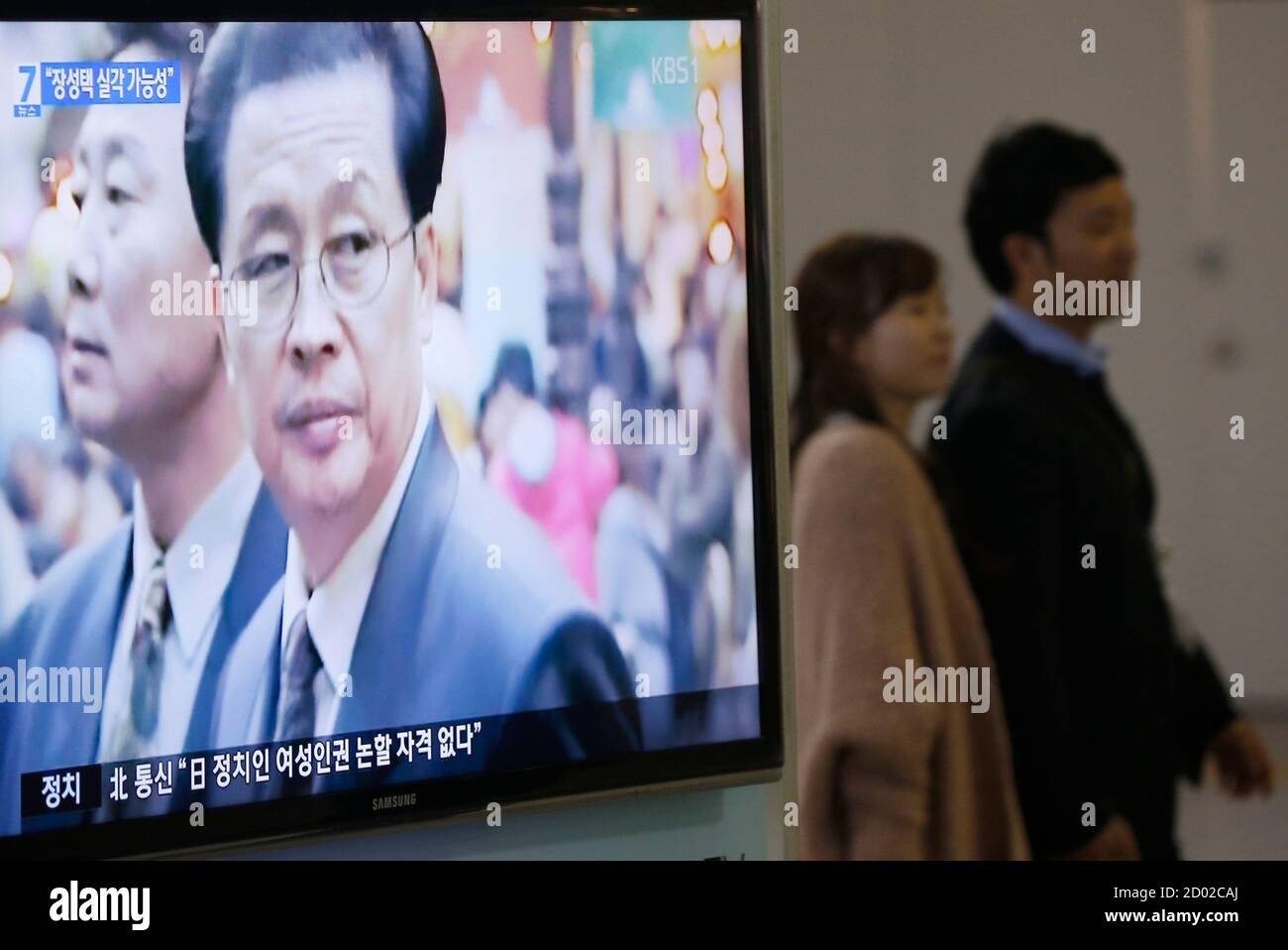 A couple walks past a television showing a report on Jang Song Thaek, North  Korean leaders' uncle, at a railway station in Seoul December 3, 2013.  North Korean leader Kim Jong Un