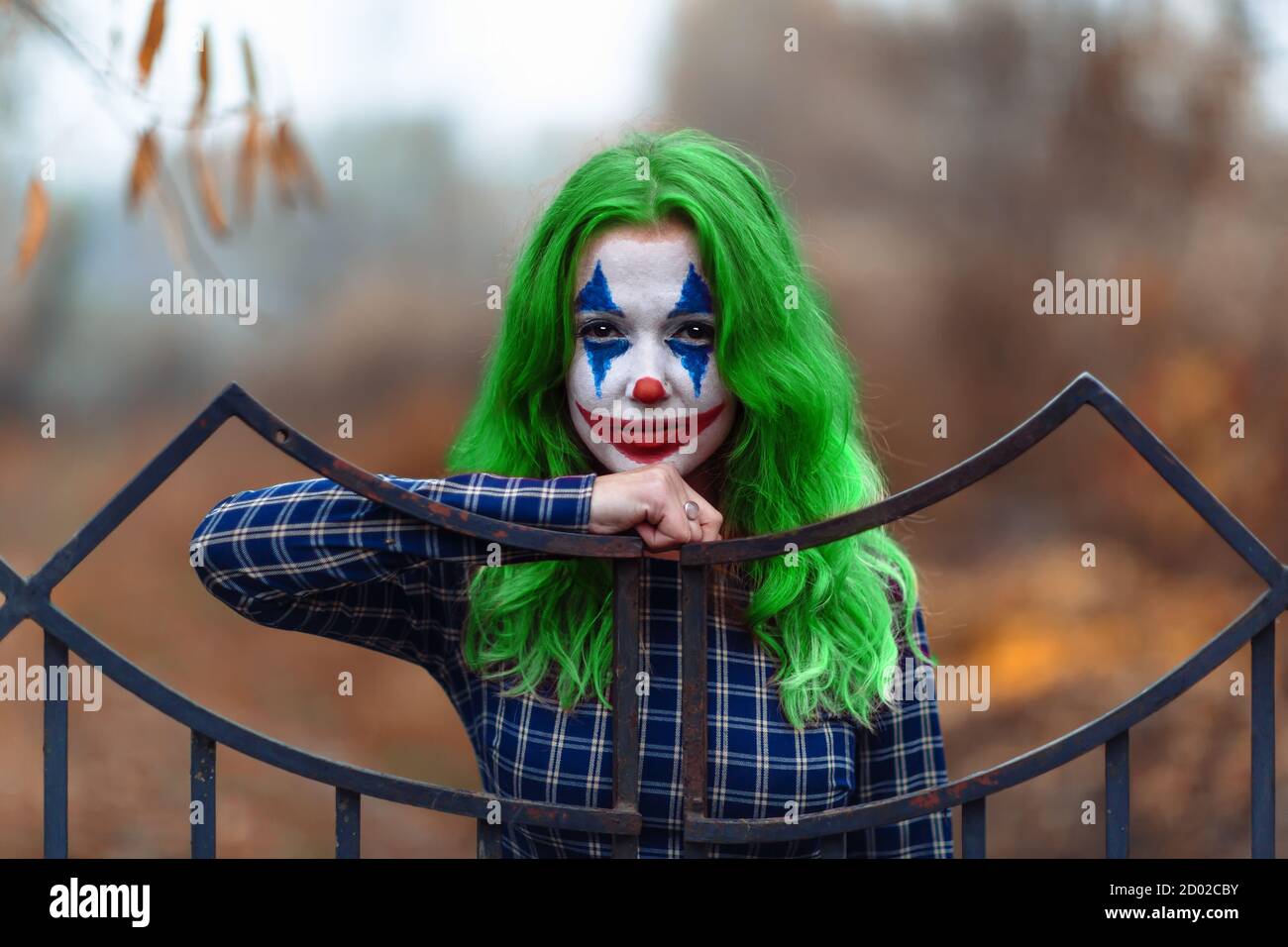 Portrait of a greenhaired girl in chekered dress with joker makeup ...