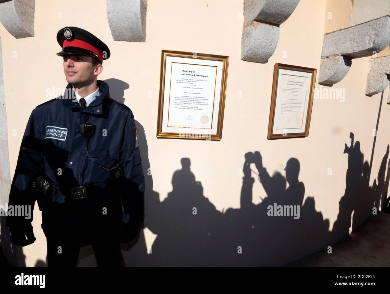Shadows of photographers are cast on the wall near a carabinieri who stands next to the official declaration of Prince Albert II announcing the birth of twins to the Prince and Princess Charlene, at Monaco Palace December 11, 2014. Princess Charlene of Monaco gave birth on Wednesday to a boy and a girl, the royal couple's first children, an aide to the royals said. According to Monaco's Constitution the boy, named Jacques, will be first-in-line to the throne, and not his twin sister, Gabriella.  REUTERS/Eric Gaillard (MONACO - Tags: ROYALS ENTERTAINMENT) Stock Photo