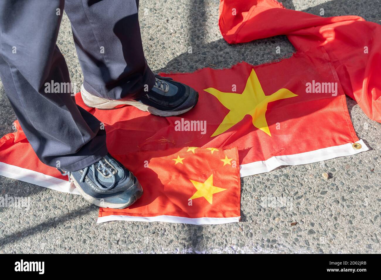 A man from Hong Kong steps on ripped-up Chinese flags at a protest against the communist government on the 71st anniversary of the communist nation. Stock Photo