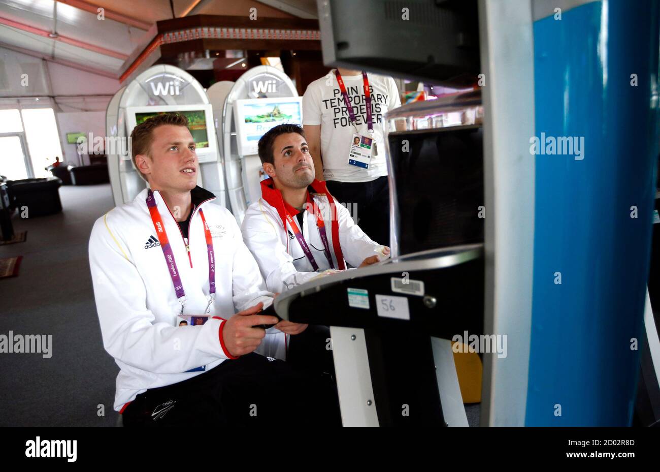 Shooter Julian Justus (C) of Germany and physiotherapist Matthias Schneider play a video game at the Athletes' Village at the Olympic Park in London,  July 19, 2012.    REUTERS/Jae C. Hong/Pool (BRITAIN - Tags: SPORT OLYMPICS) Stock Photo