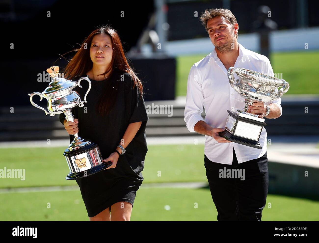 Current Australian Open tennis champions China's Li Na (L) and  Switzerland's Stanislas Wawrinka carry the men's and women's singles  trophies to the official draw ceremony at the Rod Laver Arena in Melbourne