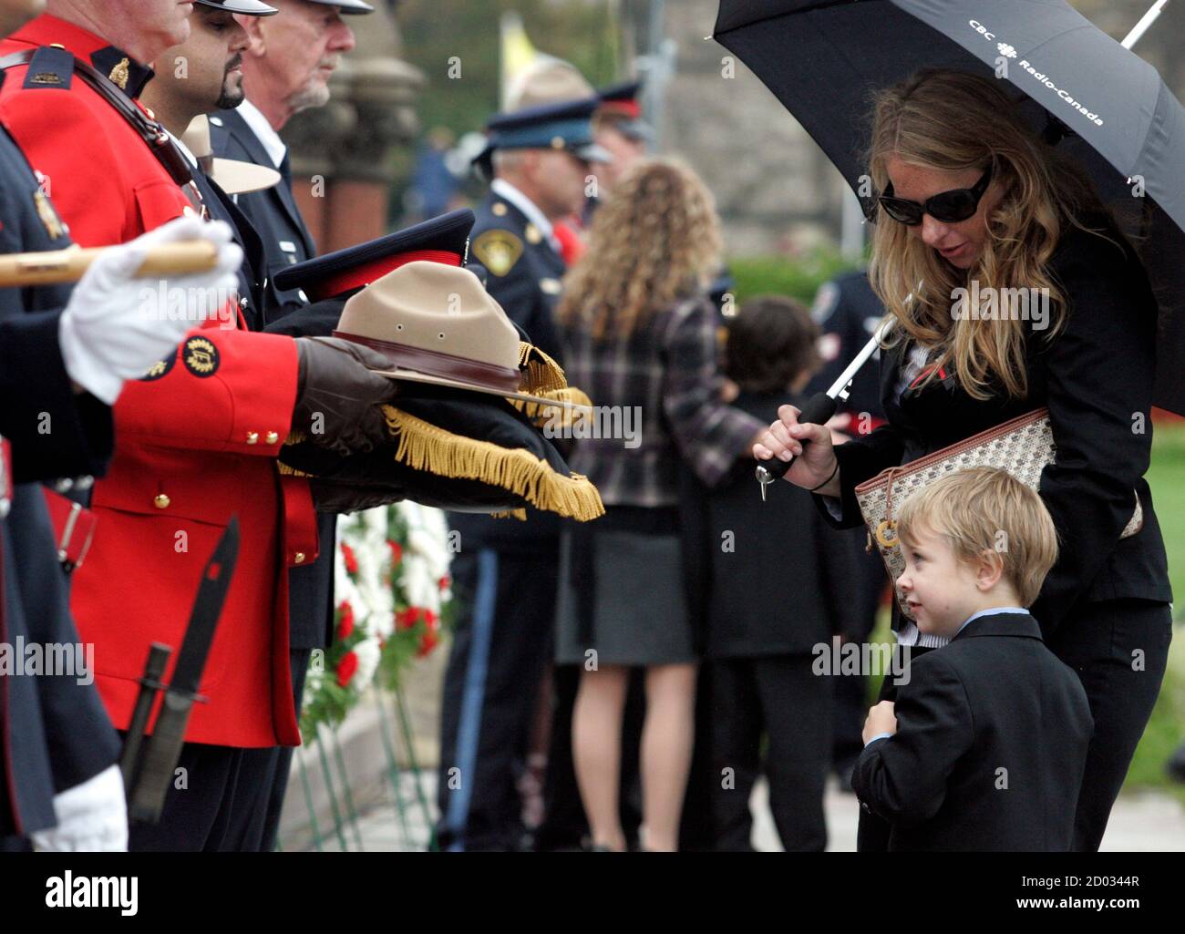 Owen Ochakovsky, the son of Peel Regional Police Officer Artem "James" Ochakovsky who was killed in March 2010 after his police cruiser was involved in a traffic accident, looks up at police officers holding hats on Parliament Hill in Ottawa, September 26, 2010. Owen and his mother Erin (also pictured) were attending the annual "Canadian Police and Peace Officer's Memorial Service" to honor police officers killed in the performance of their duties. REUTERS/Patrick Doyle (CANADA - Tags: SOCIETY) Stock Photo