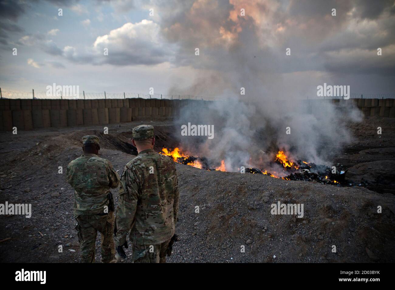 U.S. Army soldiers watch garbage burn in a burn-pit at Forward Operating Base Azzizulah in Maiwand District, Kandahar Province, Afghanistan, February 4, 2013. REUTERS/Andrew Burton (AFGHANISTAN - Tags: MILITARY) Stock Photo