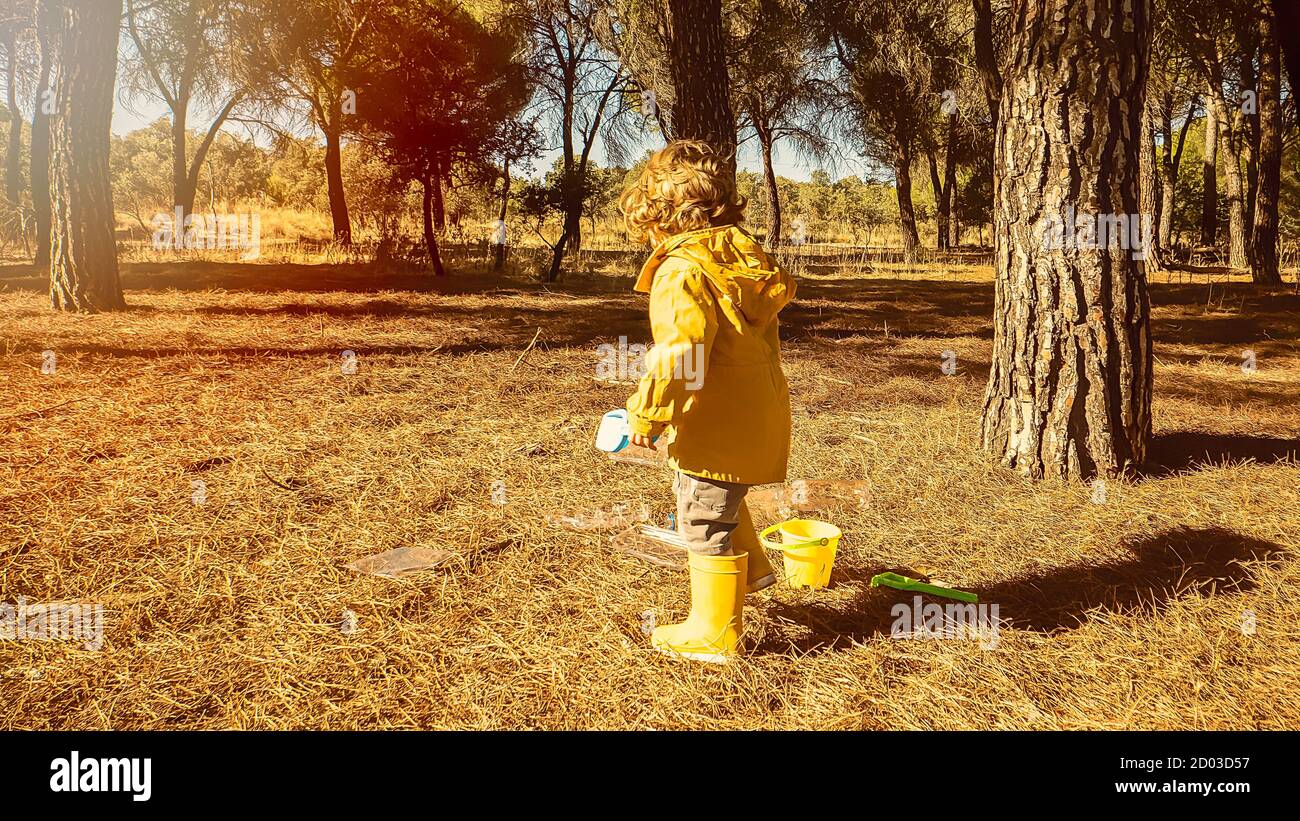 Young child is picking up plastic waste in the forest as a volunteer. Toddler and young children early environmental education concept. Plastic free Stock Photo