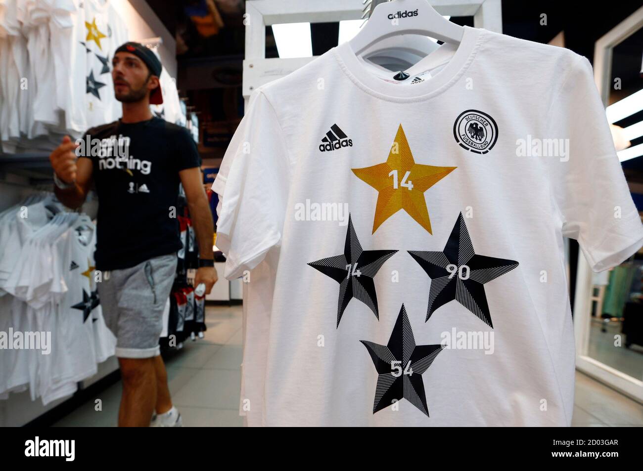 An employee walks past a memorabilia jersey of German national soccer team  showing four stars, symbolizing the number of reached World Cup  championships, at an Adidas retailer in Frankfurt July 14, 2014.