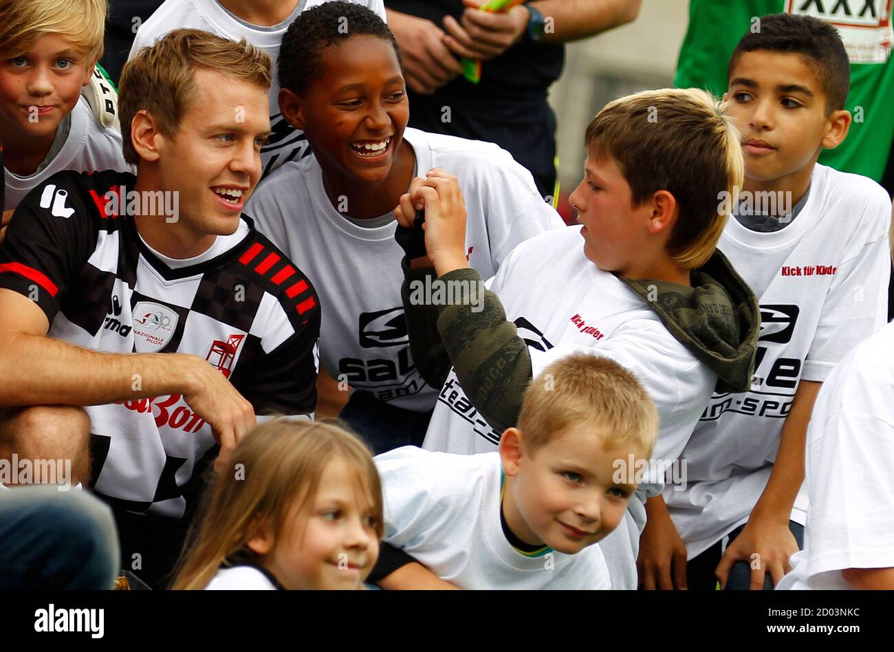 Germany S Red Bull Formula One World Champion Sebastian Vettel L Poses For A Picture With Children Prior To A Charity Soccer Match In Frankfurt July 20 2011 Vettel Is The Team
