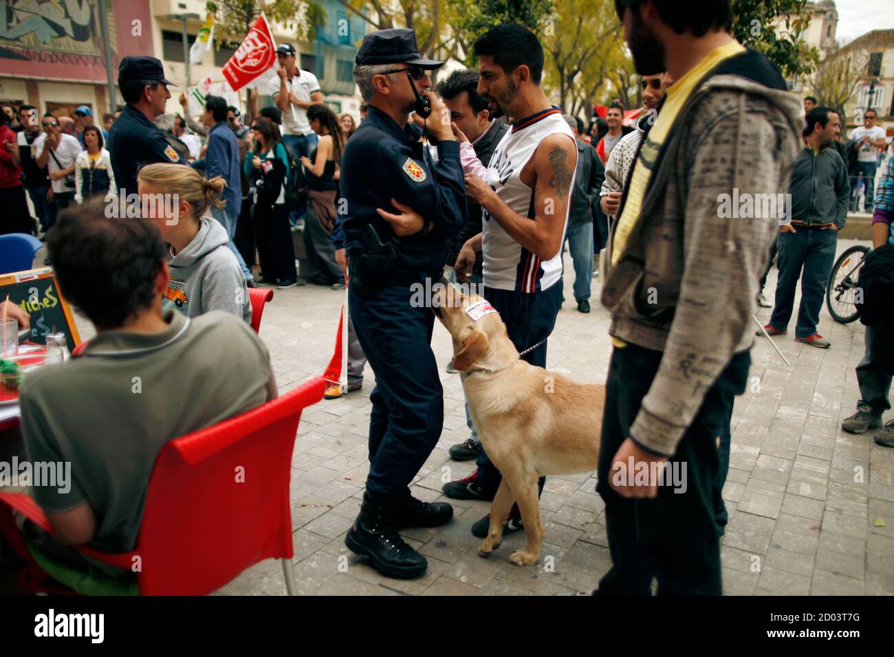 A dog smells a riot police officer as he talks with a union picketer during  a nationwide general strike in Malaga, southern Spain March 29, 2012.  Spanish workers staged a general strike