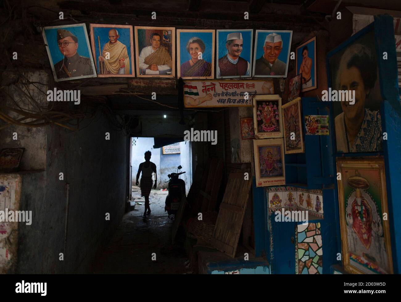 A Man Walks Through A Thoroughfare With Images Of Indian Former Politicians And Hindu Gods And Goddesses On Display At A Closed Roadside Stall Of A Local Doctor During Early Morning In A Man Walks Through A Thoroughfare With Images Of Indian Former Politicians And Hindu Gods And Goddesses On Display At A Closed Roadside Stall Of A Local Doctor During Early Morning In