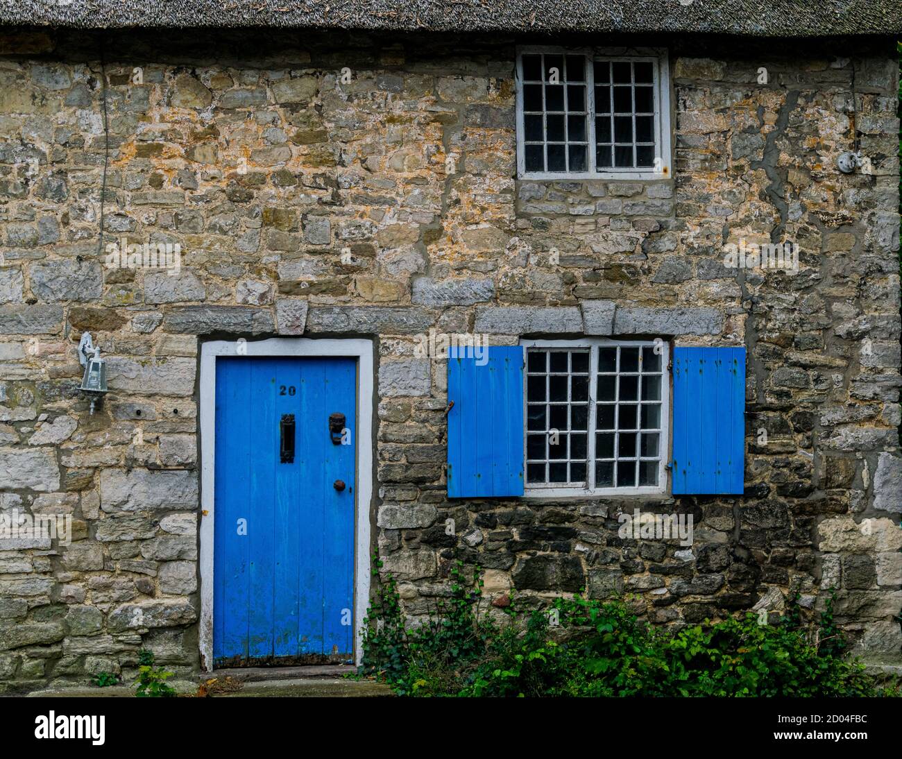 West Lulworth, United Kingdom - 19 July 2020: Beautiful thatched cottage house with cobalt blue coloured door and shutters, unique Dorset colorfull Stock Photo