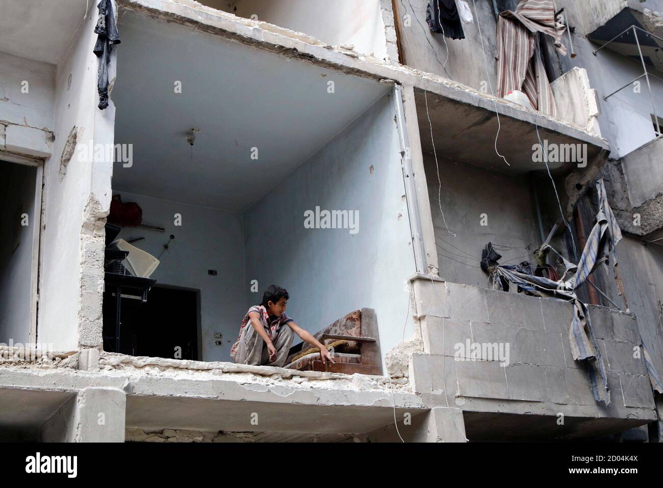 A boy crouches in a building hit by what activists said was an air strike  carried out by forces loyal to Syria's President Bashar al-Assad on Tal Al  Zarazir district in southern