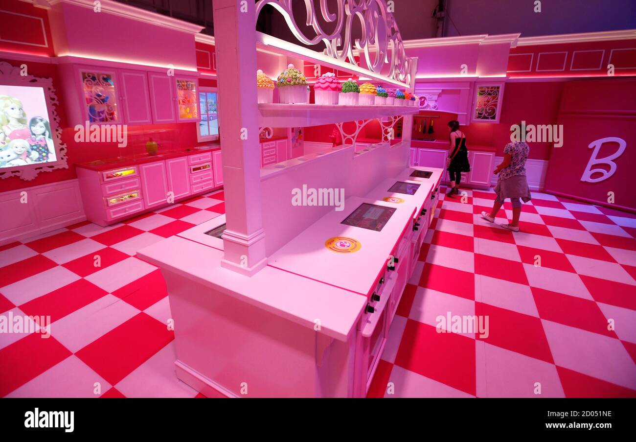 Girls watch the kitchen inside a life-size "Barbie Dreamhouse" of Mattel's  Barbie dolls during a media tour in Berlin, May 15, 2013. The life-sized  house, covering about 1,400 square metres offers visitors