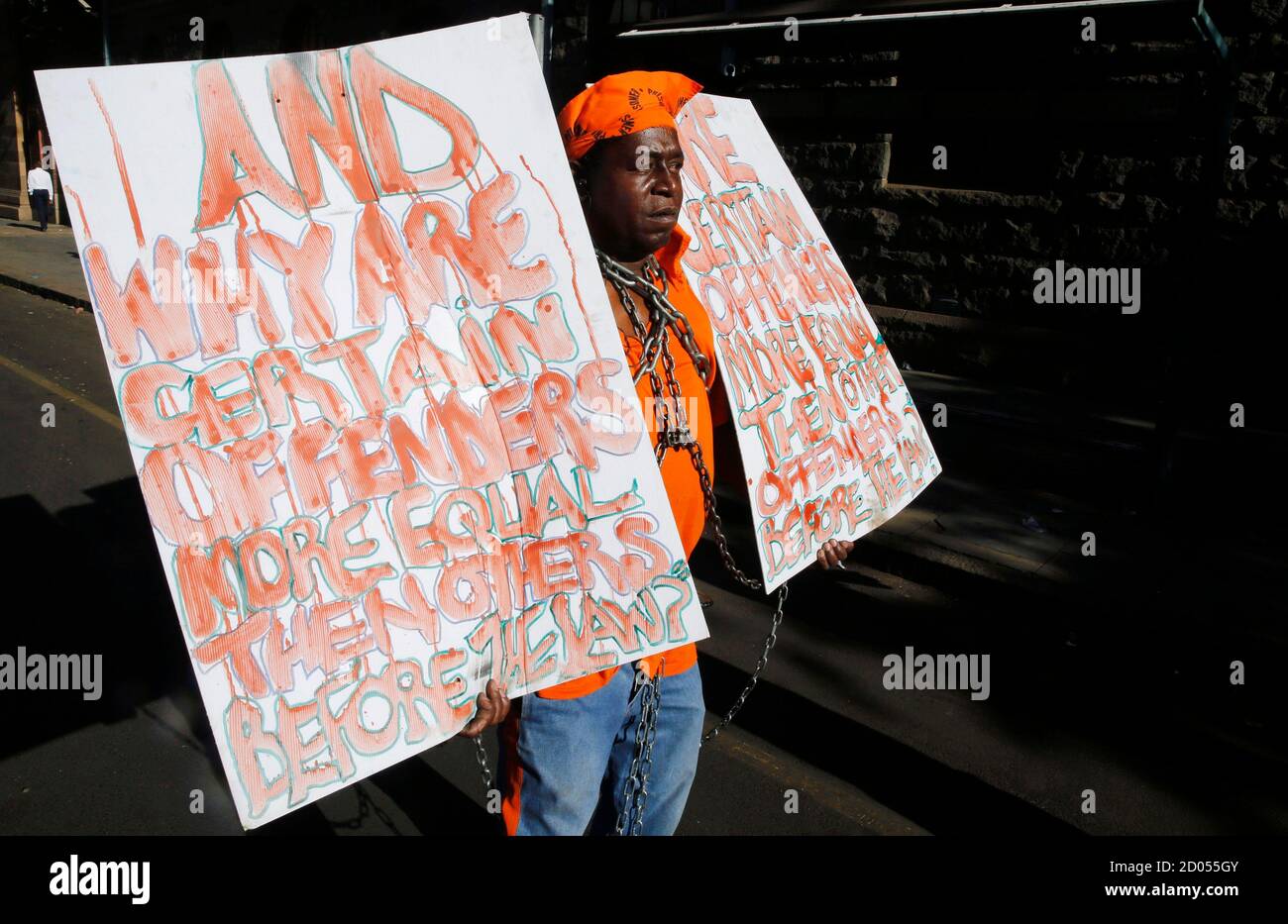 Prisoner rights activist Miles Bhudu holds placards outside the court where Oscar Pistorius was being tried in Pretoria October 21, 2014. As Pistorius spent his first day behind bars this week, a suspected child rapist and murderer went on trial at the same Pretoria court in a case that has also provoked fierce debate about crime and punishment in post-apartheid South Africa. Although the two defendants, one wealthy and white, the other poor and black, are from opposite ends of a still-divided society, both cases have revealed an alarming lack of faith in the justice system of the 'Rainbow Nat Stock Photo