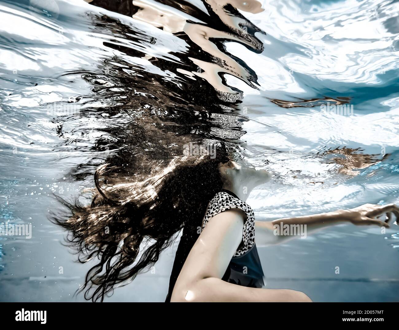 A girl's long hair flowing underwater and reflections on the