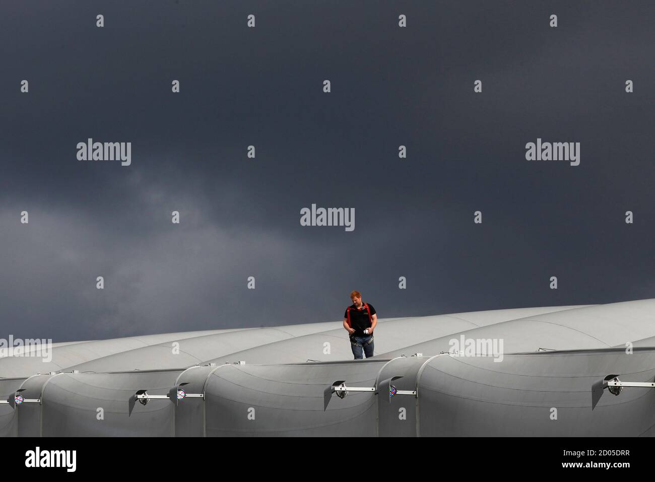 A worker stands on the roof of the Olympic water polo arena in Olympic Park, Stratford, east London, July 19, 2012. The 2012 London Olympic Games will begin in just over a week.  REUTERS/Andrew Winning (BRITAIN - Tags: SPORT OLYMPICS) Stock Photo