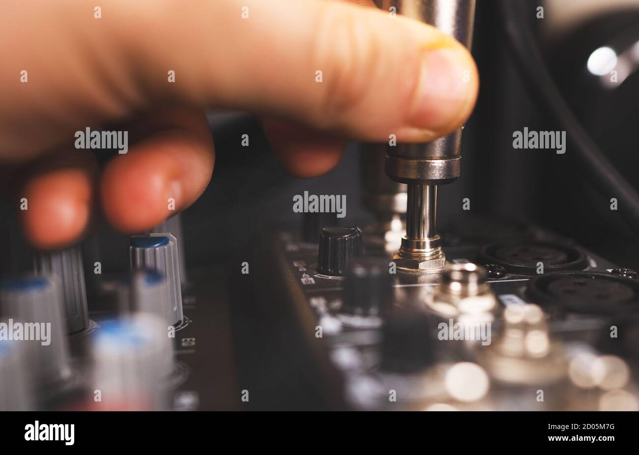Sound engineer plugging jack audio cable on studio mixer. Stock Photo