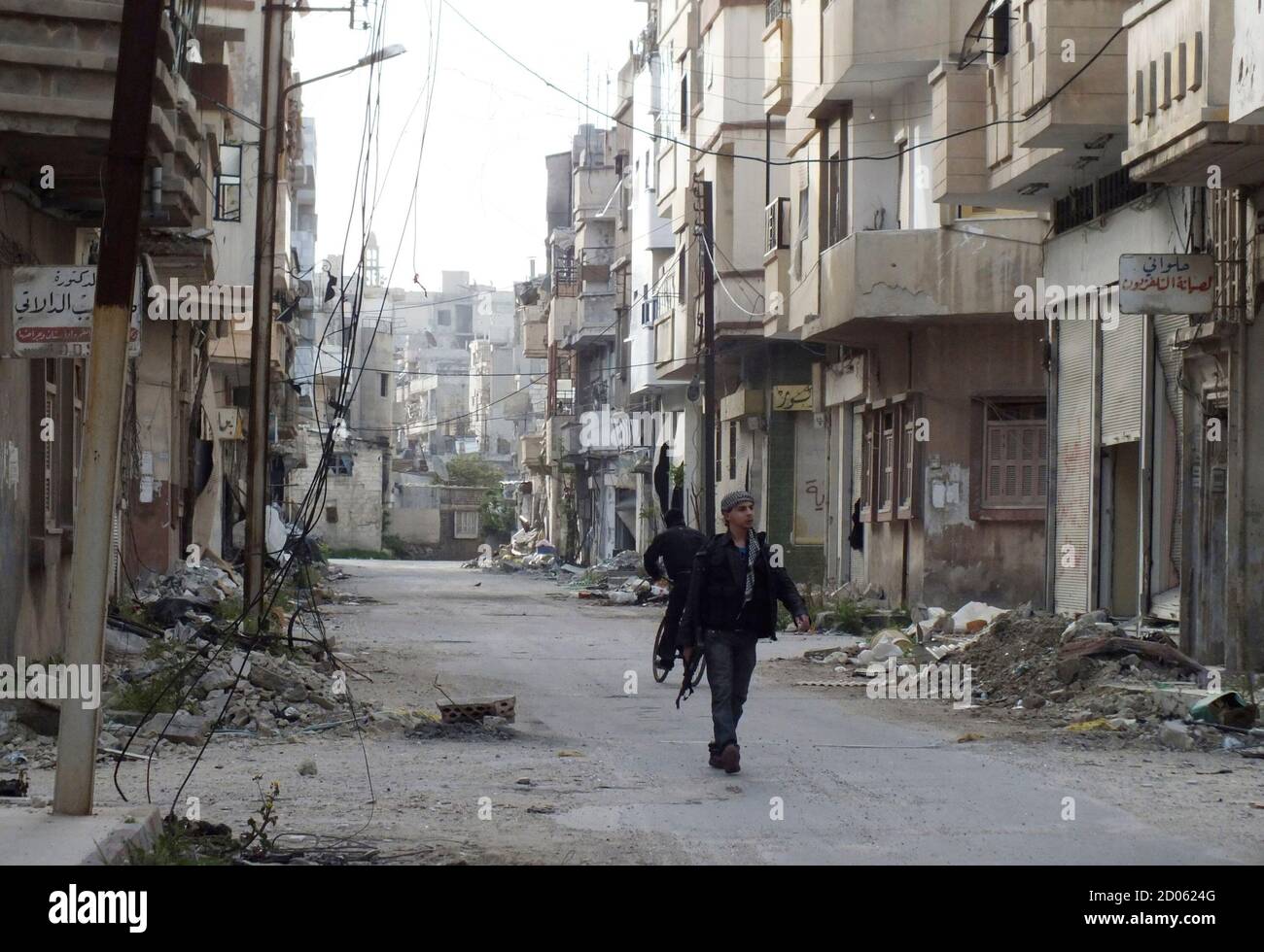 A Free Syrian Army fighter carries his weapon as he walks along a street lined with damaged buildings in Jouret al Shayah area in Homs, April 8, 2013. REUTERS/Yazan Homsy (SYRIA - Tags: POLITICS CIVIL UNREST) Stock Photo