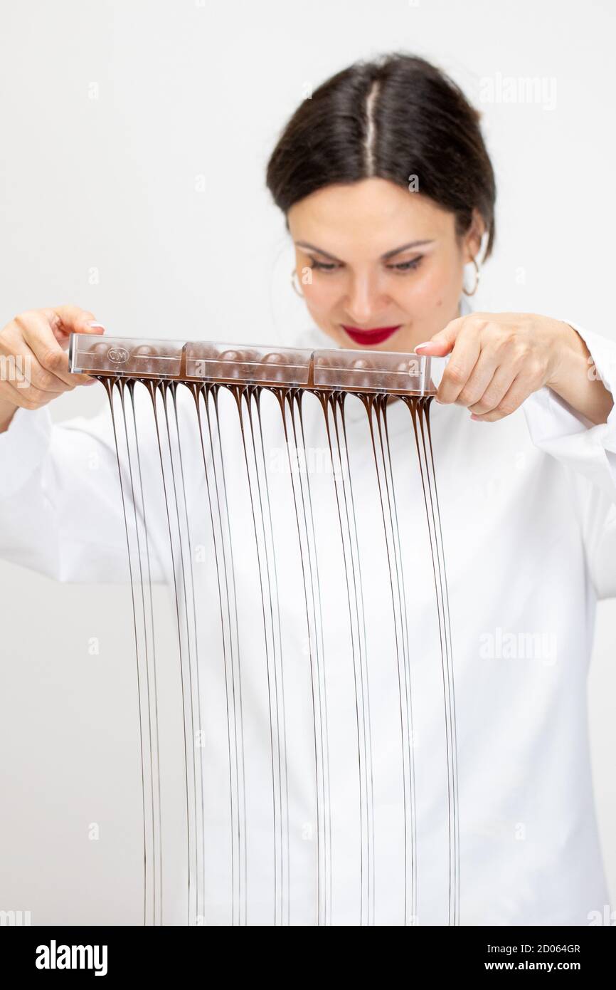 Female Confectioner pouring excess melted chocolate from molds