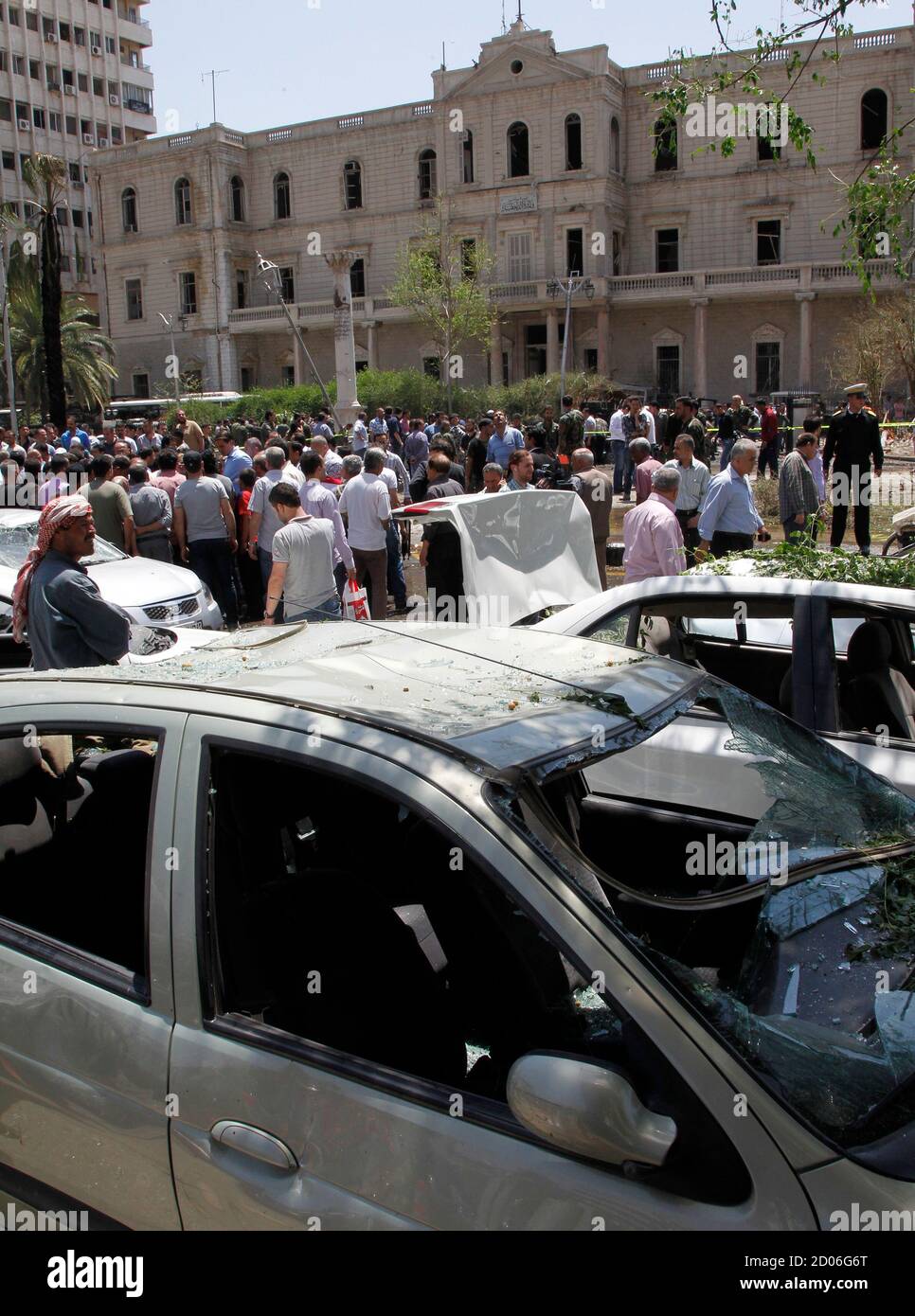 People walk on a street near the former Interior Ministry building and destroyed cars after a blast at Marjeh Square in Damascus April 30, 2013. The bomb in central Damascus killed 13 people on Tuesday, state television said, a day after Prime Minister Wael al-Halki survived an attack on his convoy in the heart of the Syrian capital. State television said 70 people were wounded, several critically. The British-based Syrian Observatory reported 9 dead civilians and 3 security men and said the death toll was likely to rise. REUTERS/Khaled al-Hariri (SYRIA - Tags: POLITICS CONFLICT) Stock Photo