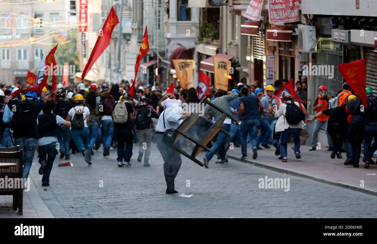 Demonstrators run for cover as riot police use tear gas to disperse them during a protest in central Istanbul September 10, 2013. Turkish police fired rounds of teargas to disperse a crowd of several hundred demonstrators rallying in central Istanbul on Tuesday against the death of a protester in the southern province of Hatay earlier in the day, witnesses said. Dozens of riot police backed by water cannon advanced down a main pedestrian avenue and some fired teargas canisters into side streets as protesters fled after the police blocked their entrance into the city's Taksim Square. As the pol Stock Photo