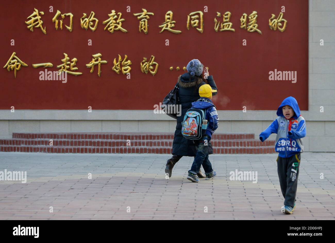 Liu Fei (L), 41-year-old warehouse worker, takes her son Xiaojie to school in Fangshan, district of Beijing, December 6, 2013. Chinese warehouse worker Liu Fei was fined 330,000 yuan ($54,200), or 14 times her yearly wage, for having a second child and her failure to pay means the boy has no access to basic rights like schooling and healthcare. Liu's desperation prompted a fruitless attempt to sell her kidney and her eight-year-old boy's plea to sell his instead. Their dilemma has now triggered a rare legal battle against the police for denying the boy a 'hukou' - household registration - due  Stock Photo