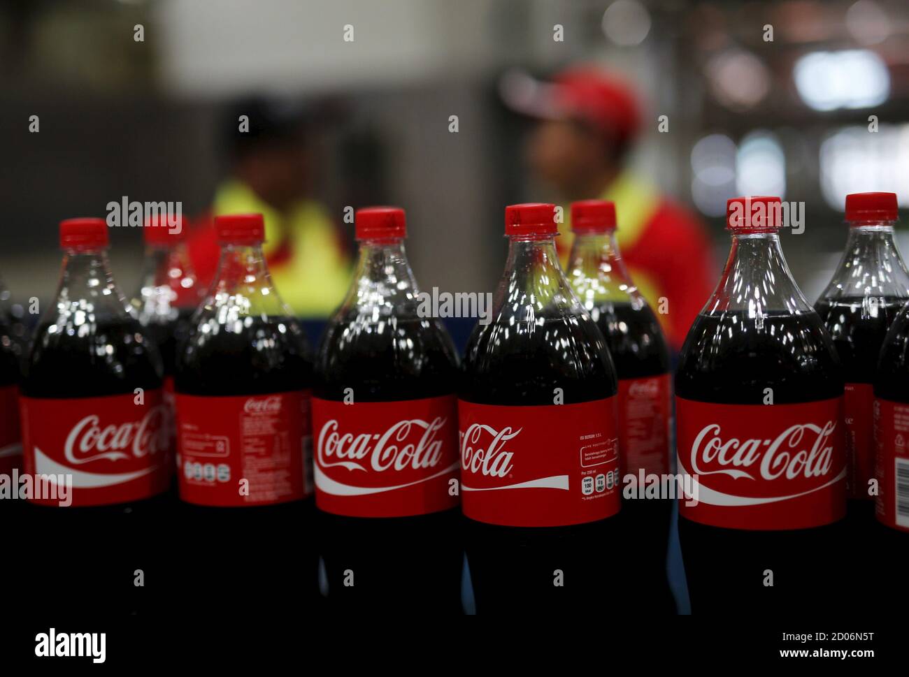 Workers stand near bottles of Coca-Cola on a newly inaugurated production line at the Cikedokan Plant in Bekasi, West Java near Jakarta March 31, 2015. The Coca-Cola company inaugurated two new production lines as part of an investment package worth some $500 million to accelerate growth in the Indonesian market.  REUTERS/Darren Whiteside Stock Photo