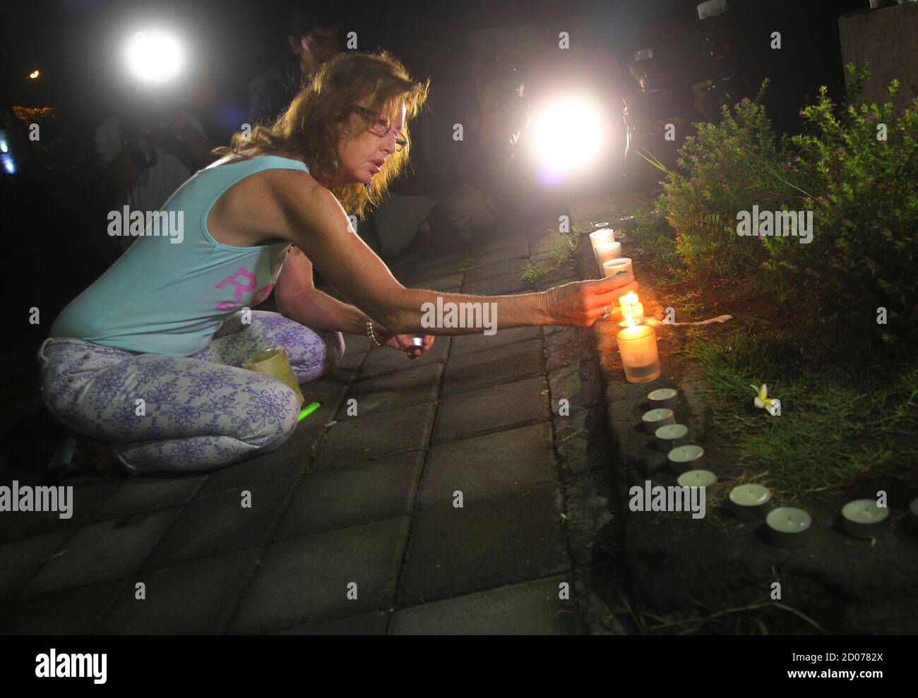 A woman lights a candle before praying in front of Kerobokan prison, before  the transfer of the two Australian death row prisoners, Myuran Sukumaran  and Andrew Chan, to the airport in Denpasar,