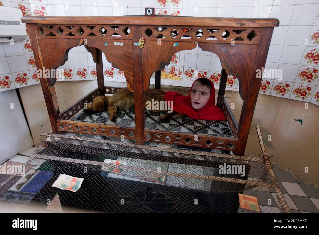 An entertainer performing as the character 'Mumtaz Begum', a fox-human hybrid creature, sits inside a wooden canopy in a small room called Mumtaz Mahal (Mumtaz Palace), to amuse visitors at Karachi Zoo in Karachi June 20, 2014. Picture taken June 20, 2014. REUTERS/Akhtar Soomro (PAKISTAN - Tags: SOCIETY ANIMALS) Stock Photo