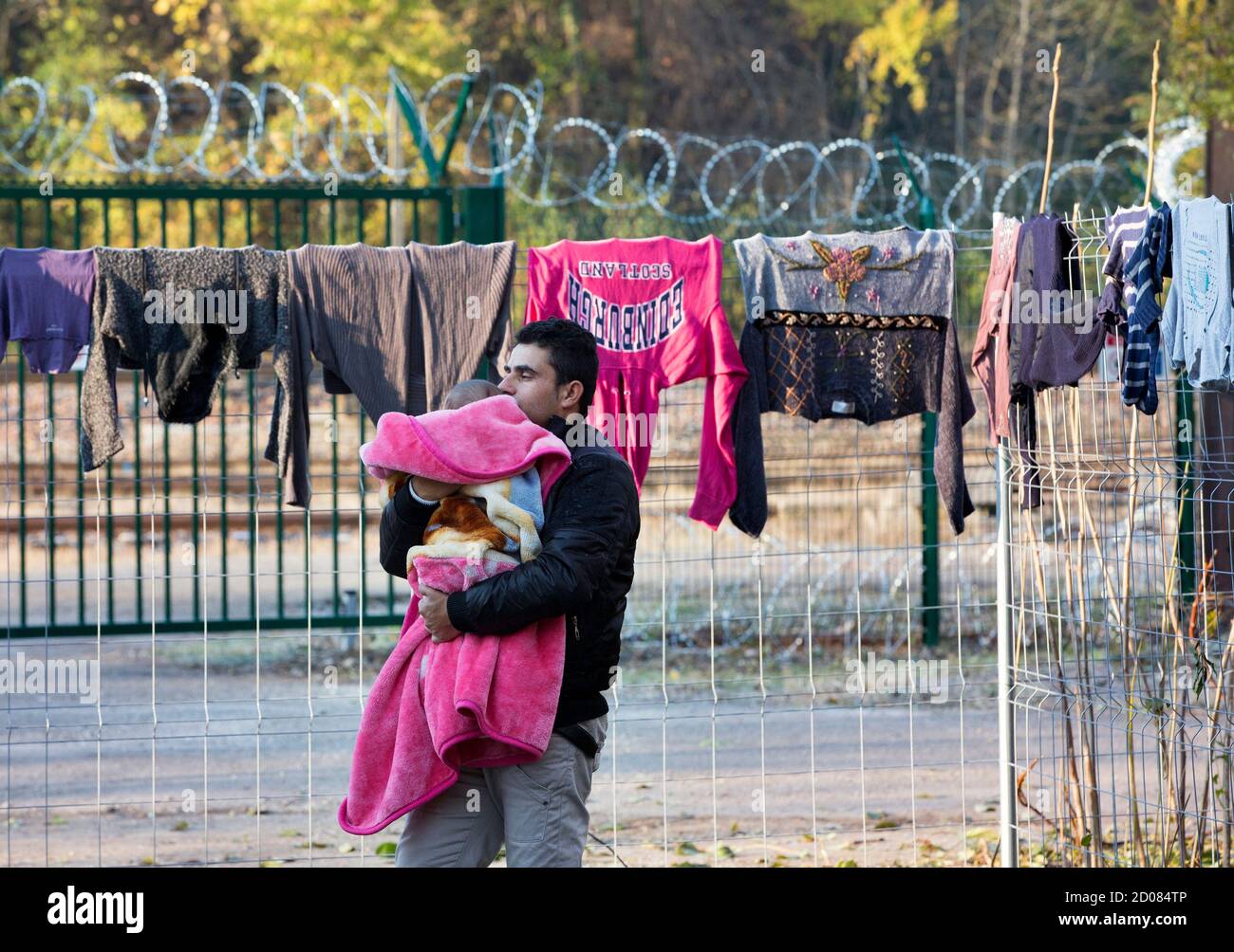 A man holds his child as he walks inside a camp for Albanian and Eastern European asylum seekers in Oullins near Lyon, southeastern France, November 28, 2013. Families live in temporary prefabricated housing set-up by French authorities after they were evacuated from an illegal camp under the A6 motorway in Lyon.   REUTERS/Robert Pratta  (FRANCE - Tags: SOCIETY IMMIGRATION POLITICS) Stock Photo