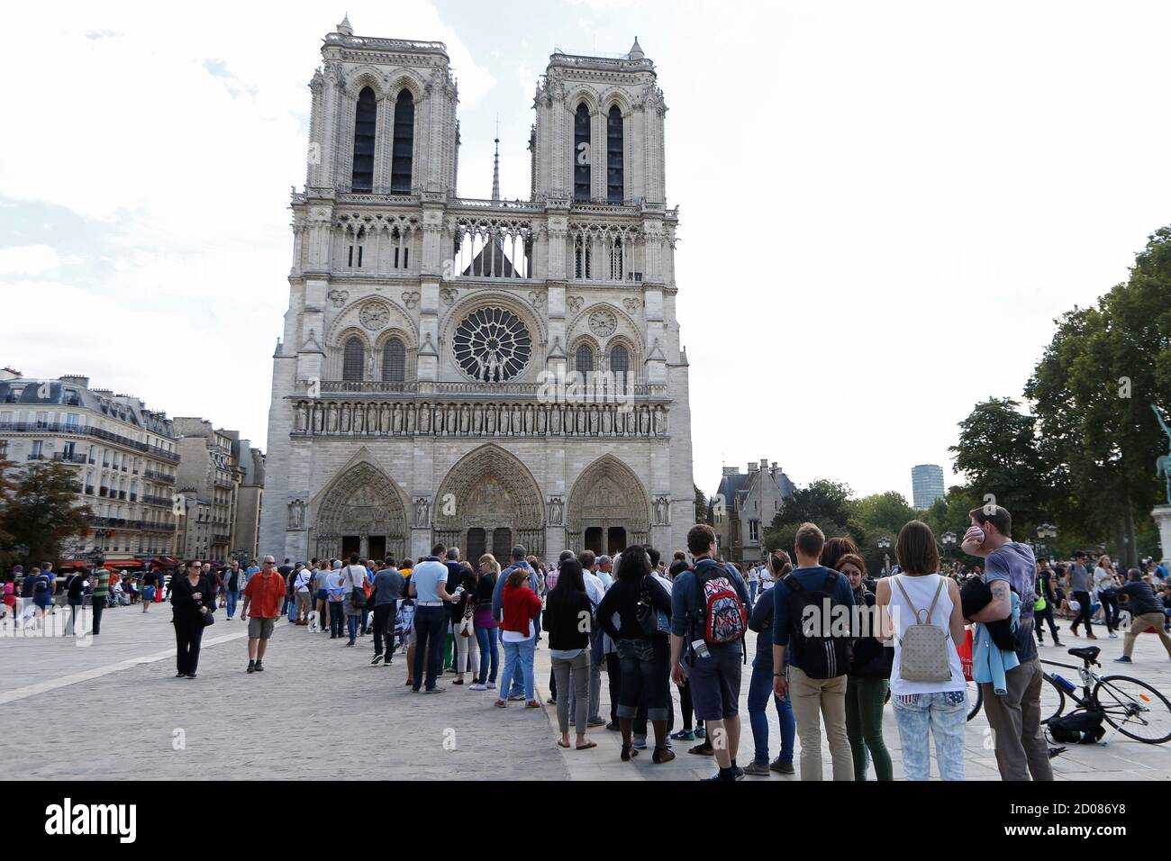People stand in line outside Notre Dame Cathedral in Paris, August 22,  2014. The cathedral greets some 13 million tourists a year according to  their official web site. The construction of the