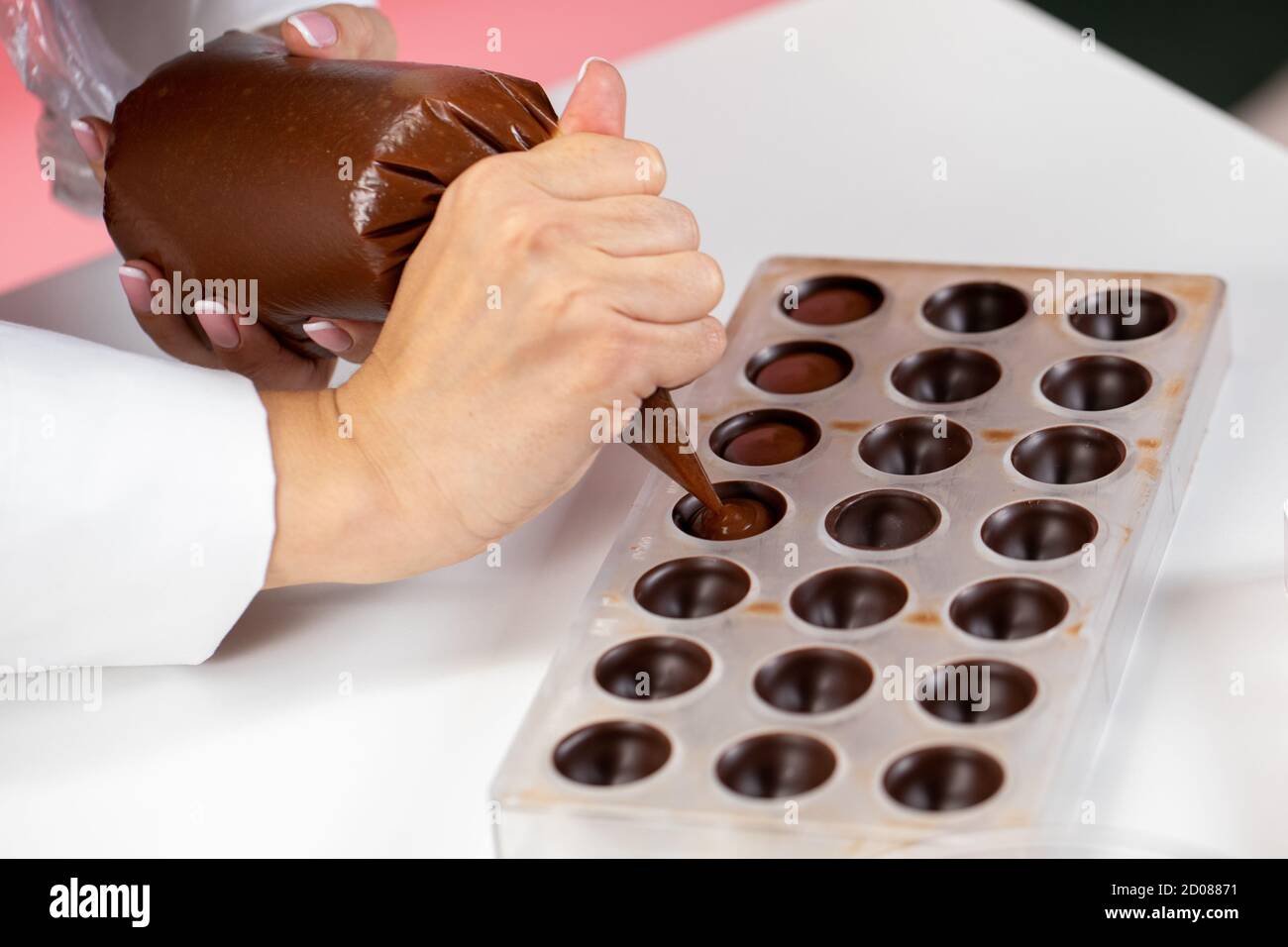 chocolatier pouring caramel filling into chocolate mold preparing handmade  candy Stock Photo - Alamy