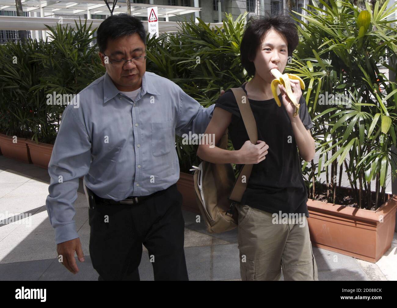 Amos Yee Eats A Banana As He Arrives With His Father To The State Courts For A Pre Trial Conference In Singapore April 17 2015 The Singaporean Has Been Charged With Harassment And