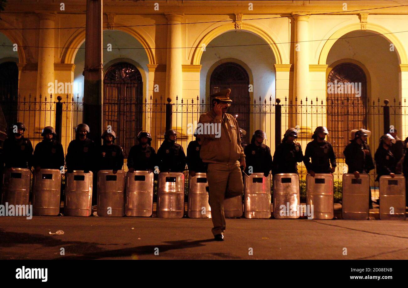 A Paraguayan policeman talks on his cellular phone in front of a line of riot policement outside the Congress in Asuncion, June 22, 2012. Paraguay's Congress removed President Fernando Lugo from office on Friday after a lightning-quick impeachment that he said was tantamount to a coup but pledged to accept. Lugo, a silver-haired former Roman Catholic bishop who quit the Church to run for president, was found guilty of mishandling armed clashes over a land eviction in which 17 police and peasant farmers were killed last week. REUTERS/Marcos Brindicci (PARAGUAY - Tags: POLITICS CRIME LAW) Stock Photo