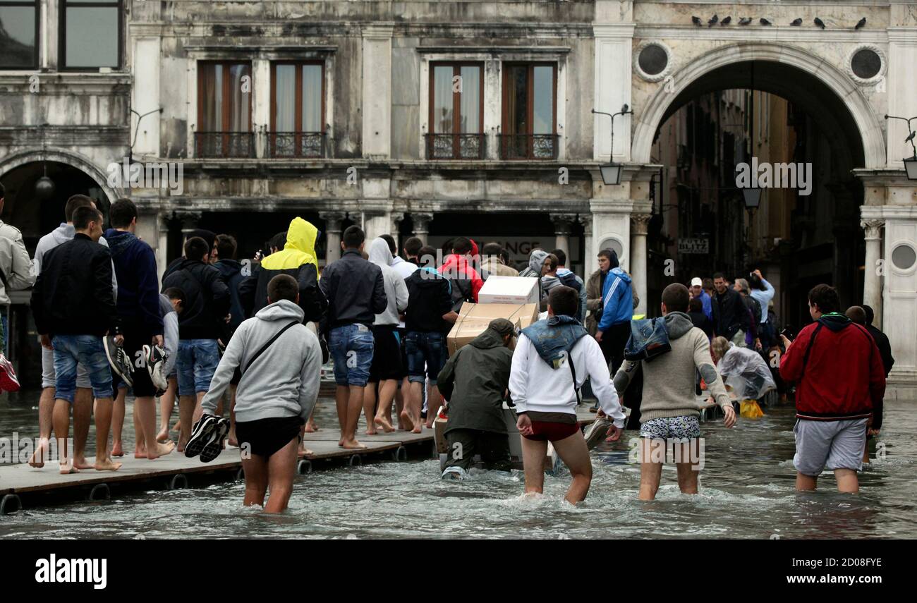 Tourists walk on raised platforms for flood waters in St. Mark Square  during a period of seasonal high water in Venice October 27, 2012. The  water level in the canal city rose