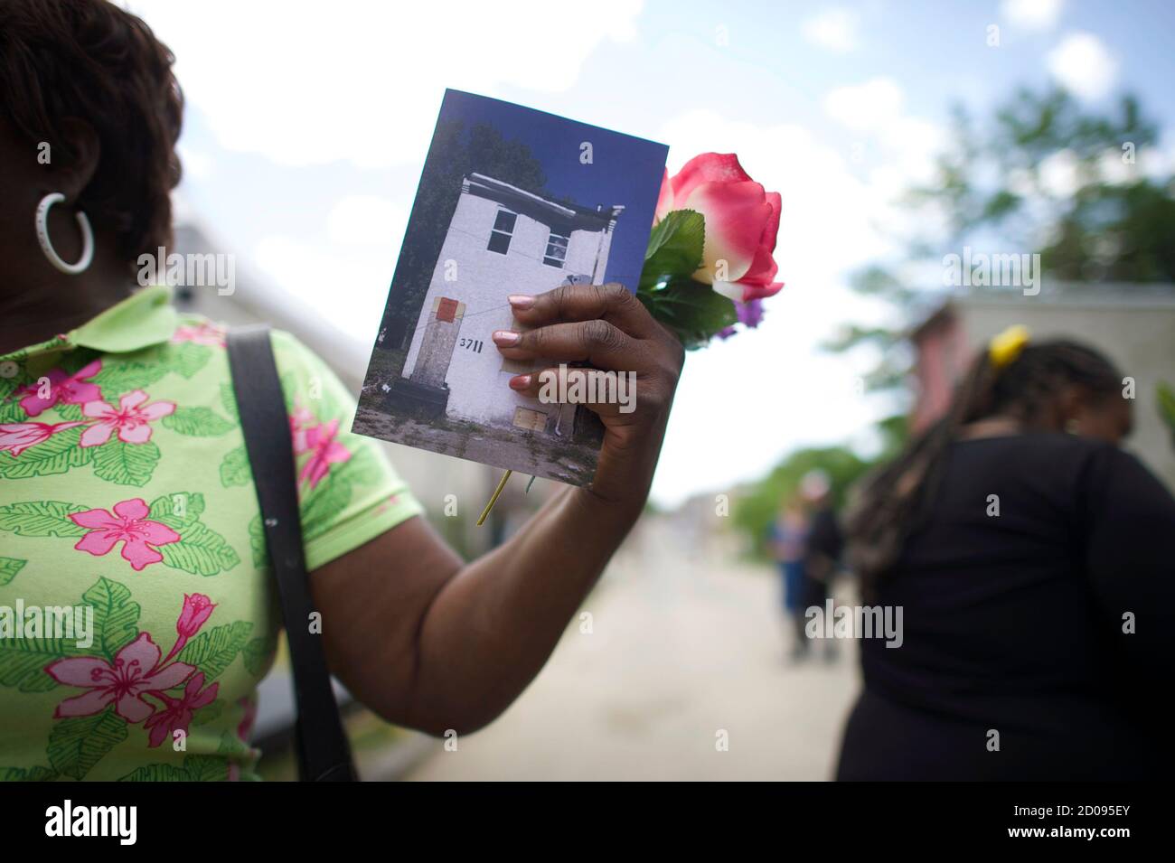 Local resident Anita Whitley, 61, holds a program and flower at 'Funeral for a Home,' a tribute for a dilapidated row house which survived 142 years and outlived many of its neighbours, in Mantua, Philadelphia May 31, 2014. Mourners came to 3711 Mellon Street in the Mantua section of Philadelphia to pay their respects to its history and to a once vibrant neighborhood that has experienced decades of decline. Organized in part by Philadelphia's Temple University, the event mixed art and public history to honor the lives of ordinary residents.   REUTERS/Mark Makela (UNITED STATES - Tags: SOCIETY) Stock Photo