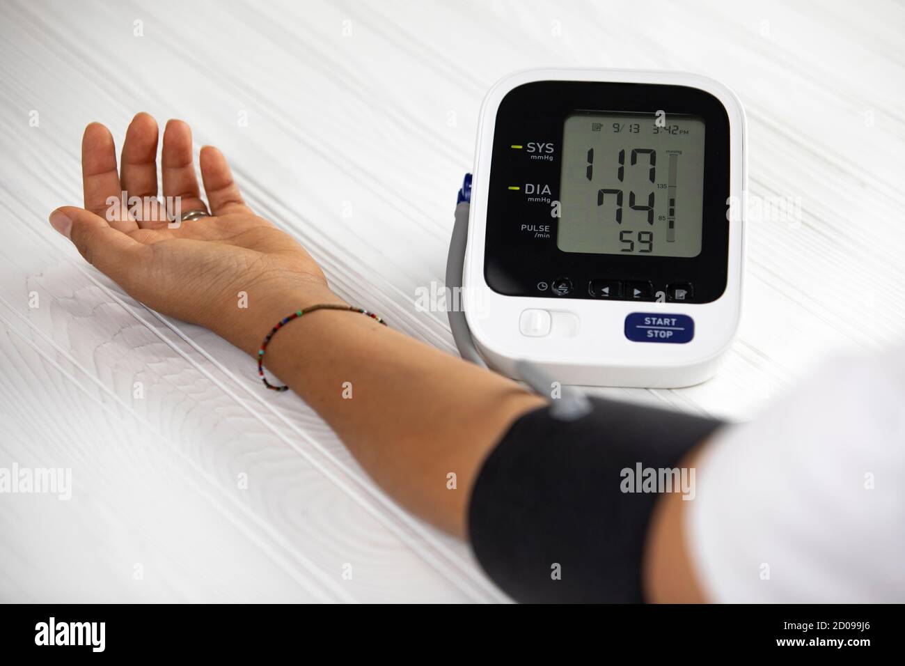 Woman measuring his own blood pressure, white wood Stock Photo