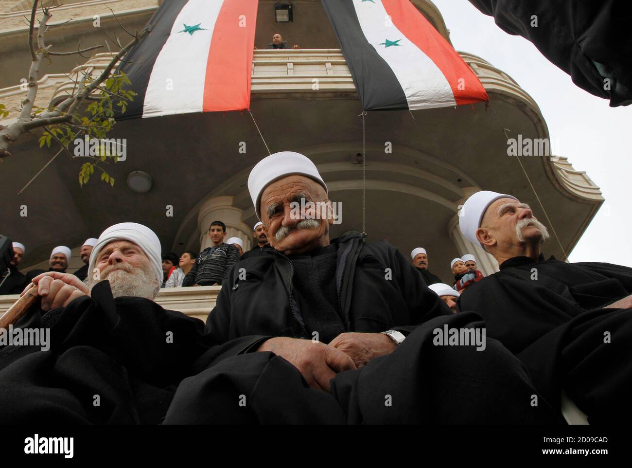Members of the Druze community sit under Syrian flags during a rally in the Druze village of Majdal Shams on the Golan Heights, which stand at the heart of a long-standing conflict between Israel and Syria, February 14, 2012. Hundreds of members of the Druze community took part in the rally on Tuesday, marking the 31st anniversary of Israel's annexation of the strategic plateau which it captured in the 1967 Middle East War. REUTERS/Baz Ratner (CIVIL UNREST POLITICS ANNIVERSARY) Stock Photo