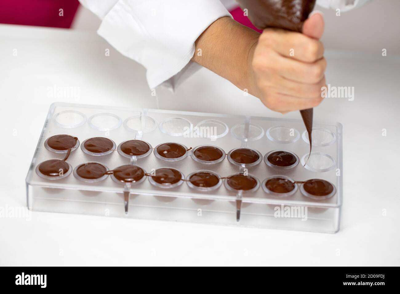 Closeup pouring melted chocolate into mold with pastry bag, hand