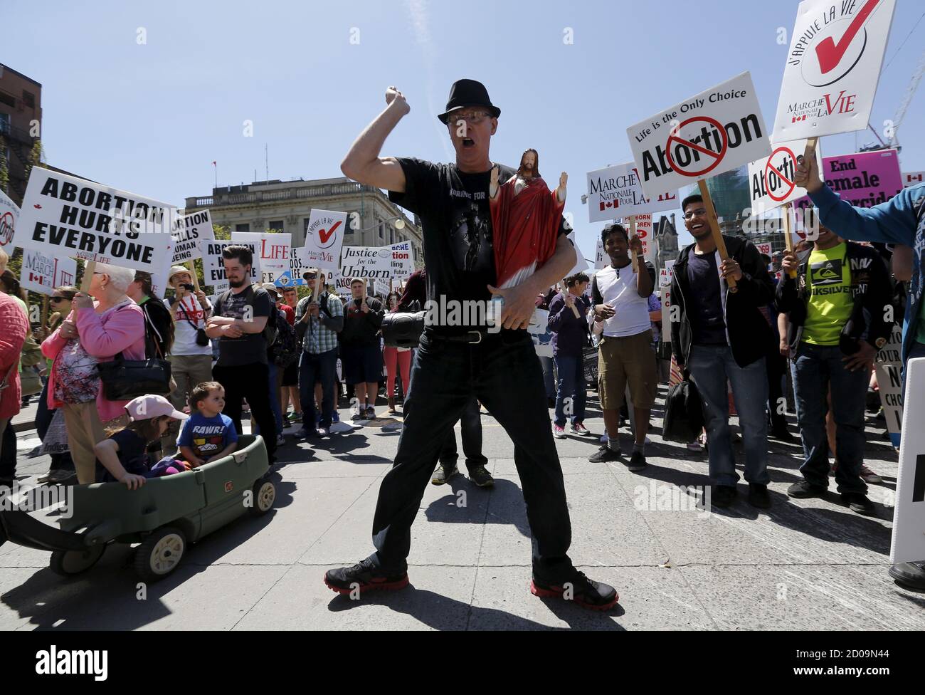 Andre Levesque dances while holding a statue of Jesus during an anti-abortion protest in Ottawa May 14, 2015. REUTERS/Chris Wattie Stock Photo